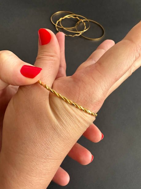 золотой браслет. женские руки носят золотой браслет. женская рука выбирает один из золотых браслетов группы и носит его - 16609 стоковые фото и изображения