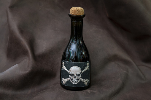 small bottle of poison, label with white skull on black background