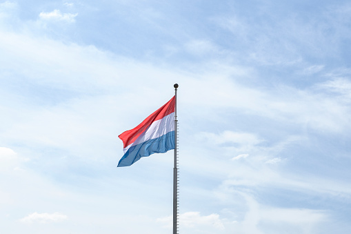 Fluttering flag of the Kingdom of Luxembourg  against a blue sky