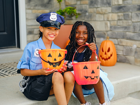 Elementary aged girls wearing costumes for trick or treating on Halloween.