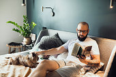 Reading a book in cozy bedroom with a cute dog lying near