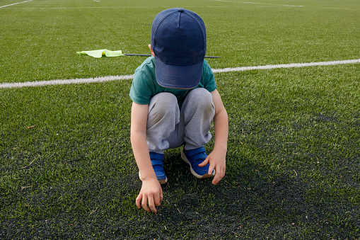 Soccer field, artificial green grass, boy and yellow flag in the corner.