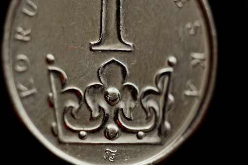 One Czech koruna coin close-up isolated on black background. Detail of metallic money close up. European country money Czech Republic.