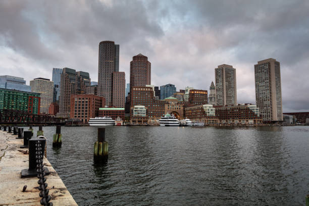 Boston USA - 17 March 2025. Modern waterfront buildings with docks and reflections on a calm, cloudy day in Boston
