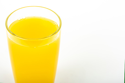 Orange juice yellow-orange in glass isolated on white