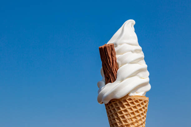 A close up of an ice cream cone against a blue sky in summer