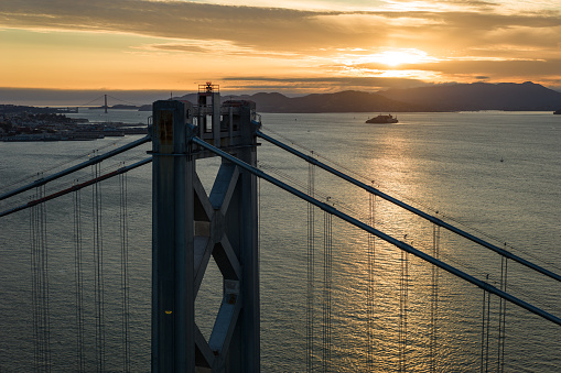An aerial shot of the San Francisco-Oakland Bay Bridge taken by drone at sunset.