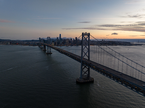 An aerial shot of the San Francisco-Oakland Bay Bridge taken by a drone during the sunset.