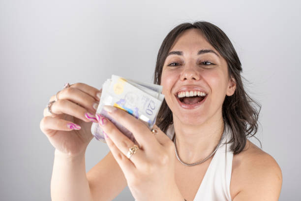 Portrait of a happy young woman counting British 20 pounds Portrait of a happy young woman counting British 20 pounds twenty pound note stock pictures, royalty-free photos & images