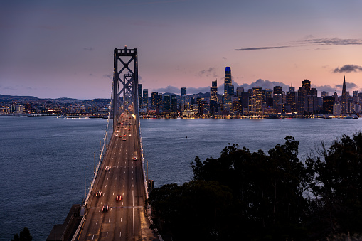 An aerial view of the San Francisco skyline seen from the San Francisco-Oakland Bay Bridge at dusk.