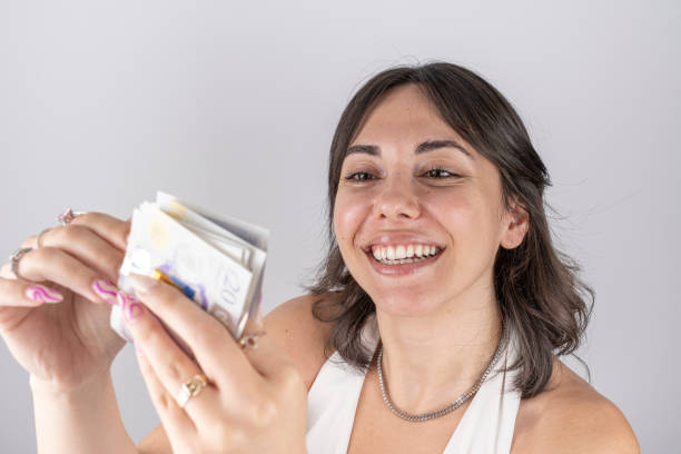 Portrait of a happy young woman counting British 20 pounds Portrait of a happy young woman counting British 20 pounds twenty pound note stock pictures, royalty-free photos & images