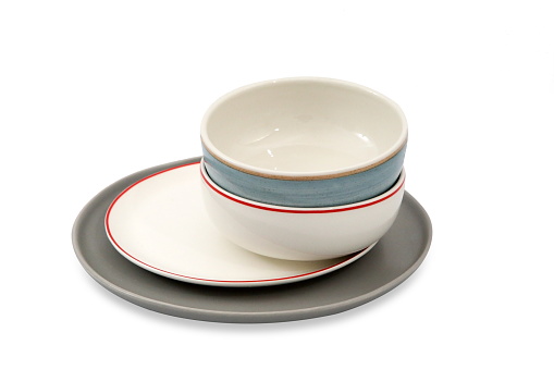 Modern tableware set with cutlery and a vibrant blue plate, with glasses, overhead flat lay shot. Trendy dinnerware on a white marble background