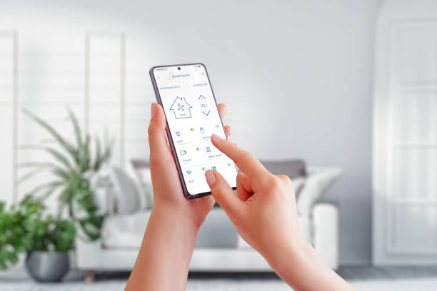 istock Smart home management with a mobile phone in a woman's hand, seamlessly connecting to a smart home app while surrounded by the comfort of a stylish living room 1499060046