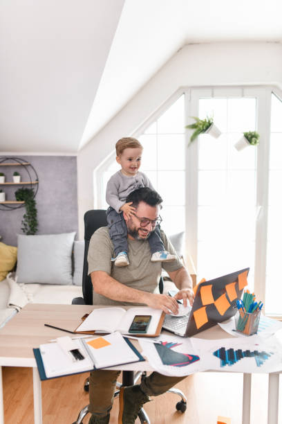 istock Father Carrying Baby Boy On Shoulders While Writing Articles On Laptop 1499060269