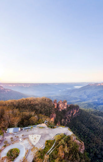 Clear sky over Three sisters rock formation in Blue Mountains of Australia in aerial vertical panorama over Echo point lookout.