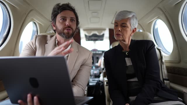Coworkers talking while use laptop in a corporate jet