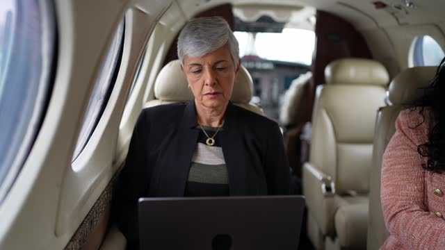Senior businesswoman using laptop in a corporate jet