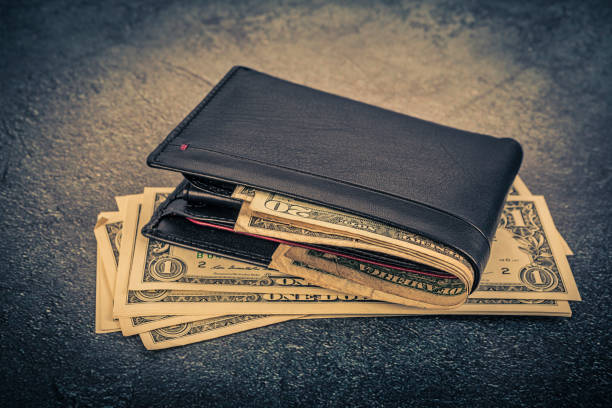 istock Black leather wallet with dollar bills on asphalt background. Toned. 1499088682