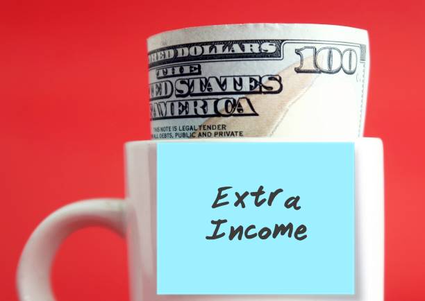 istock Dollar money cash banknote in a white cup on red background with blue sticky note written EXTRA INCOME . Concept of find second job to earn more 1499091124