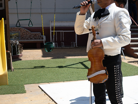 close up of a Mariachi holding a violin while singing mexican music in a public event traditional party