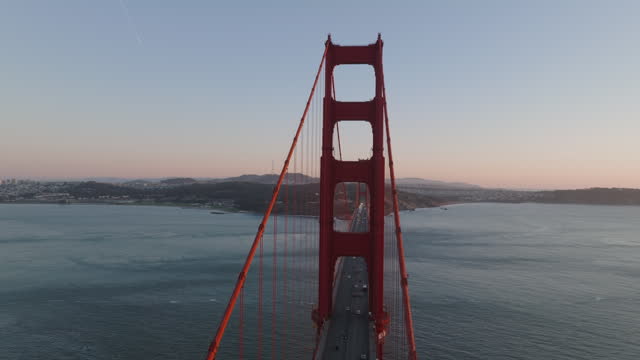 Aerial slide and pan footage of long suspension bridge over strait. Famous red Golden Gate Bridge. San Francisco, California, USA