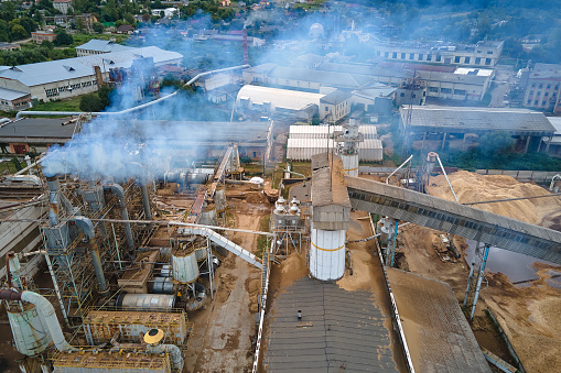 Aerial view of wood processing plant with smokestack from production process polluting environment at factory manufacturing yard.