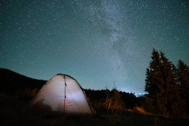 istock Bright illuminated tourist tent glowing on camping site in dark mountains under night sky with sparkling stars. Active lifestyle concept. 1499102687