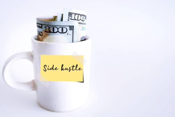 istock White ceramic cup with cash dollars money inside on white copy space background with note written Side Hustle, financial goal to make extra earning or second income from side business or part time job 1499107271