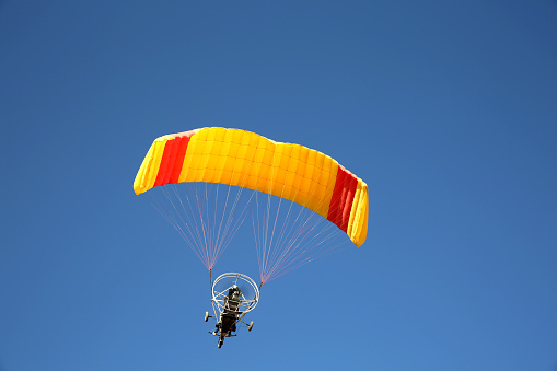 Hang glider pilot flying towards under bright blue wing and sky in February 2019 Mount Maunganui New Zealand