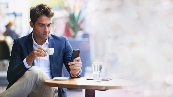 Businessman, coffee shop and phone for networking with mockup space, reading and focus at table. Man, smartphone and espresso with communication, social media app and texting on web chat ux at cafe