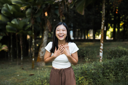 Portrait of a beautiful young  Asian woman looking  laughing at camera with nature  background.