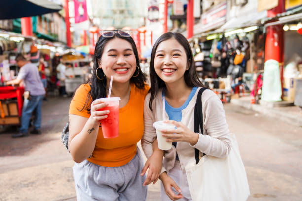 istock Asian girls enjoying a drink while walking through city. 1499112853