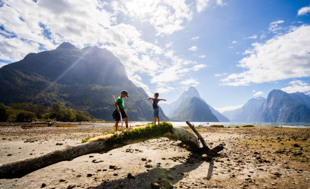 istock Kids walking on log with Mitre Peak in background. 1499118291