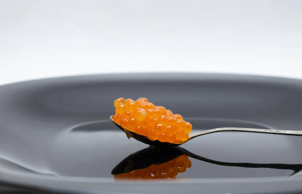 黒い皿の接写に赤いサーモンキャビアのスプーン - caviar salmon red gourmet ストックフォトと画像