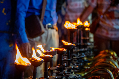 LIne of fire oil lamps on the ghat of ganga in rishikesh where people take blessings by passing their hands over the fire in Hinduism
