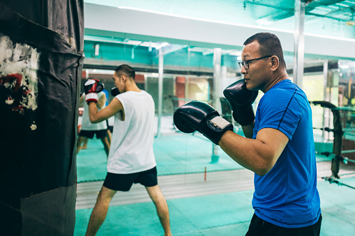 Two Asian boxing enthusiasts are engaged in self-training, dedicating themselves to improving their skills and physical fitness.