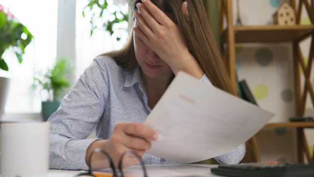 Exhausted frustrated woman sit at desk with paper bills, feeling stressed about bank loan payments, worrying of unpaid taxes, financial problems