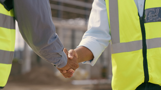 People, architect and handshake for deal in construction, partnership or teamwork success on site. Engineer, builder or contractor shaking hands in collaboration for project or architecture