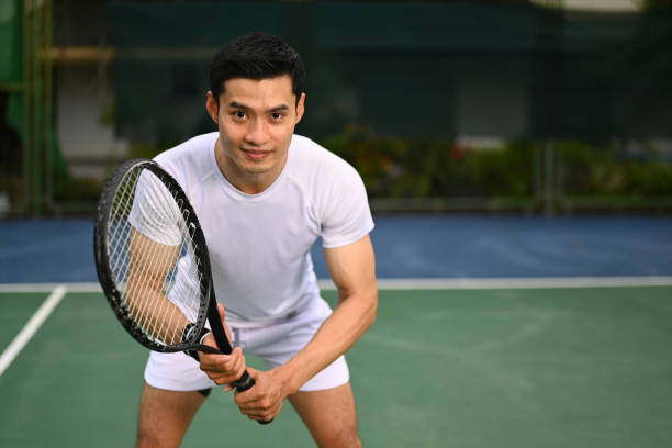 istock Focused male tennis player crouching in ready position and holding racket while waiting for serving ball from competitor. 1499140108