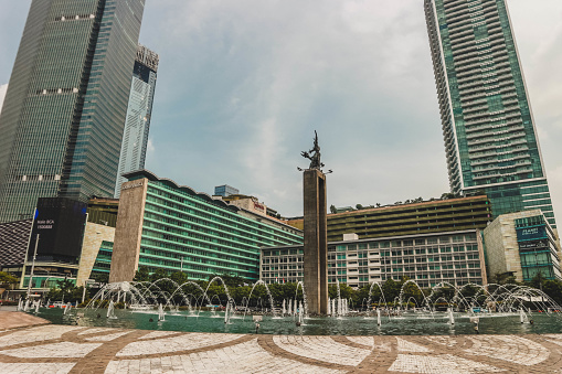 Jakarta, indonesian - june 18, 2023 : photos of the welcome monument statue with a multi store building in jakarta as the background