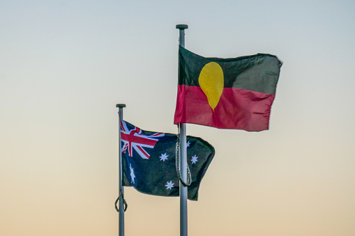 The Australian and Australian Aboriginal flags fly at Bondi Icebergs Club, Bondi Beach, Sydney.  This image was taken from the coastal walkway at sunset on a cold, sunny winter day on 17 June 2023.
