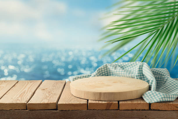 istock Empty wooden podium with tablecloth on table over tropical beach bokeh background.  Summer mock up for design and product display 1499145987