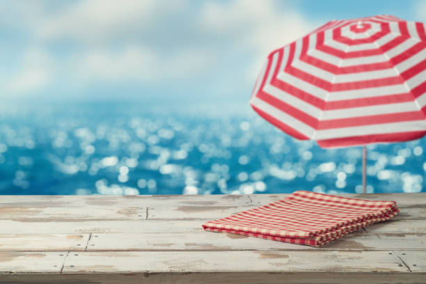 istock Empty wooden table with red tablecloth on table over blurred sea beach background. Summer mock up for design and product display 1499145989