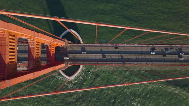 Top down panning footage of traffic on famous red suspension bridge. Golden Gate Bridge over water in bay. San Francisco, California, USA