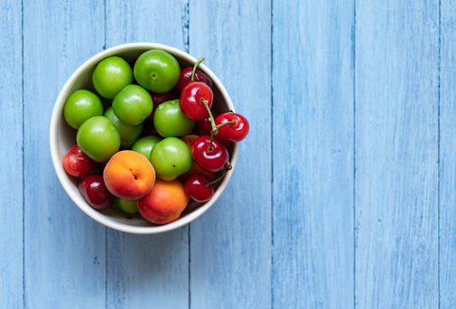 heap of fresh garden cherries in the bowl isolated on pastel background, close-up