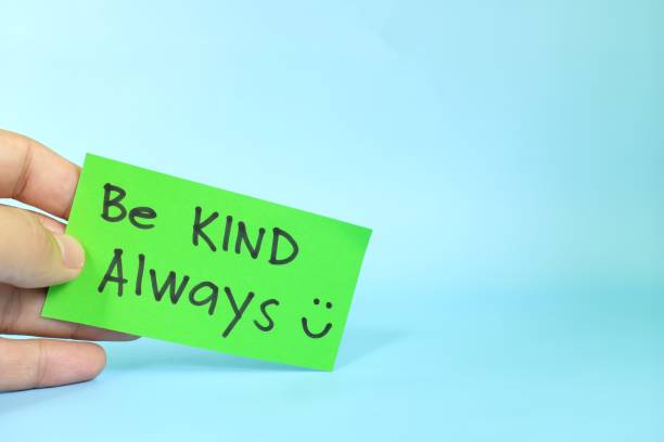 Be kind always reminder concept. Hand holding a bright green paper message note.