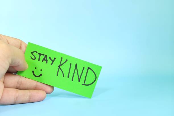 istock Stay kind and kindness reminder concept. Hand holding a bright green paper message note. 1499149435