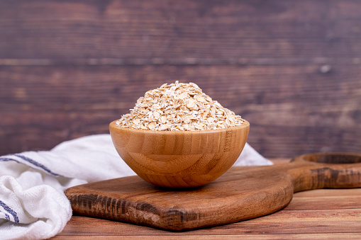 Oatmeal or Oat flakes on wooden background. Oatmeal in wooden bowl