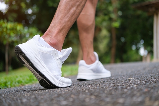 Close up view of urban runner feet running on on the street. Fitness, workout and healthy lifestyle concept.