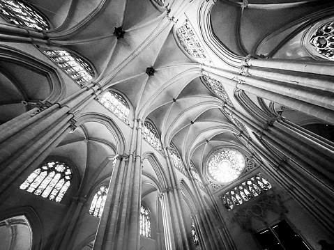 Ceiling and rose window inside the Cathedral of Toledo, in black and white. Sunlight enters through the rose window.